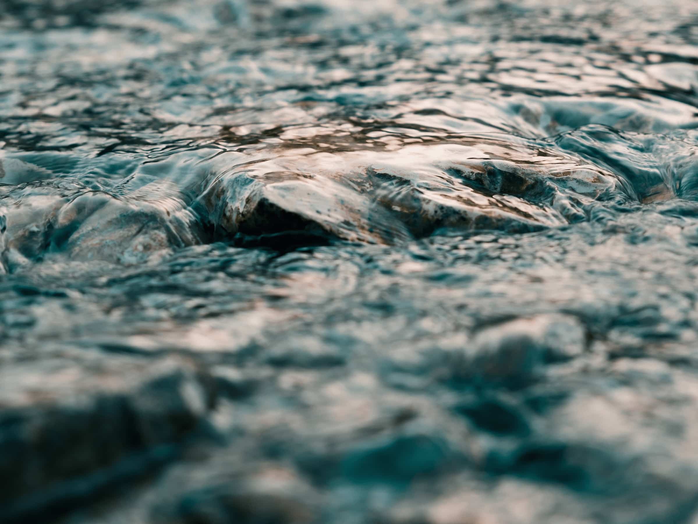 Texturierte Oberfläche des Wassers mit Reflexionen und kleinen Wellen, die das Licht brechen